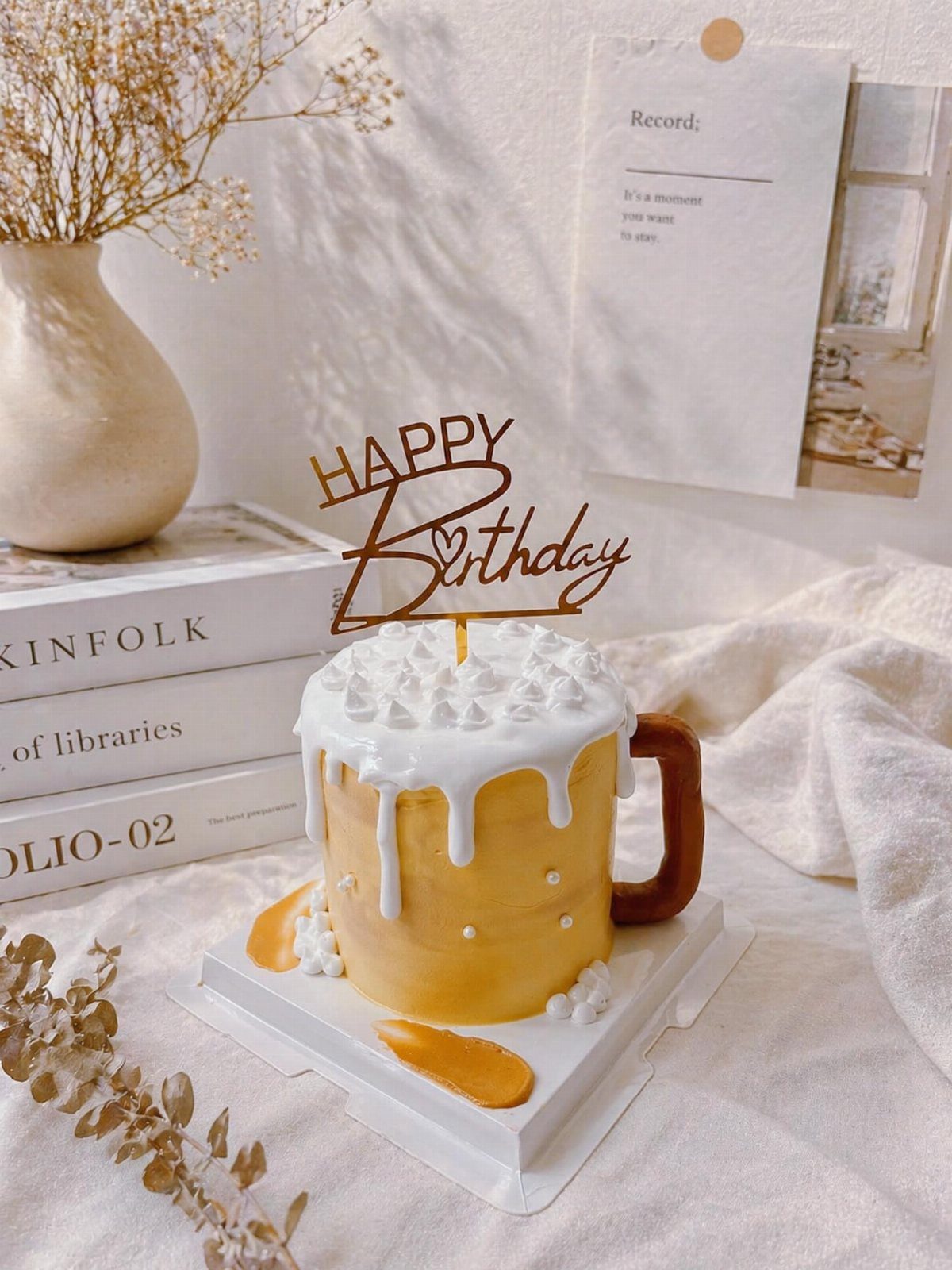Beer mug cake with white foam frosting and a gold Happy Birthday topper.