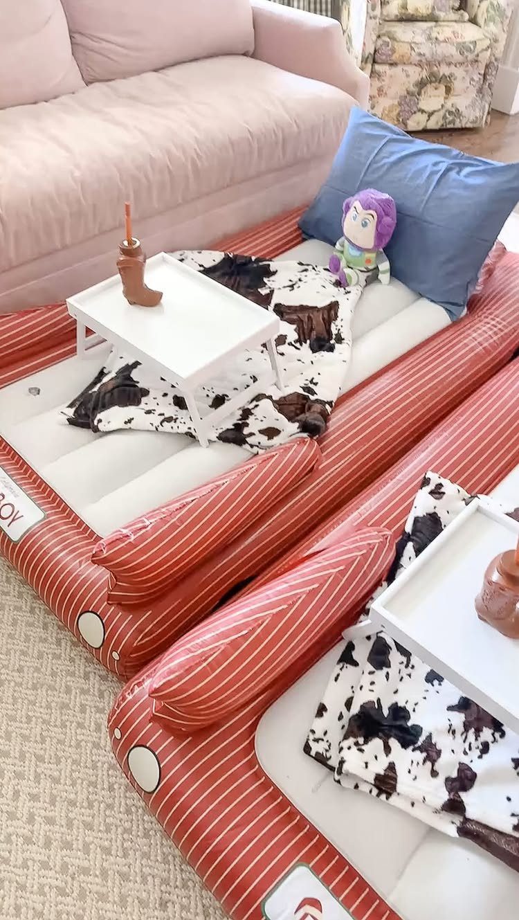 Inflatable red striped lounge beds with cow-print blankets and small white tray tables.