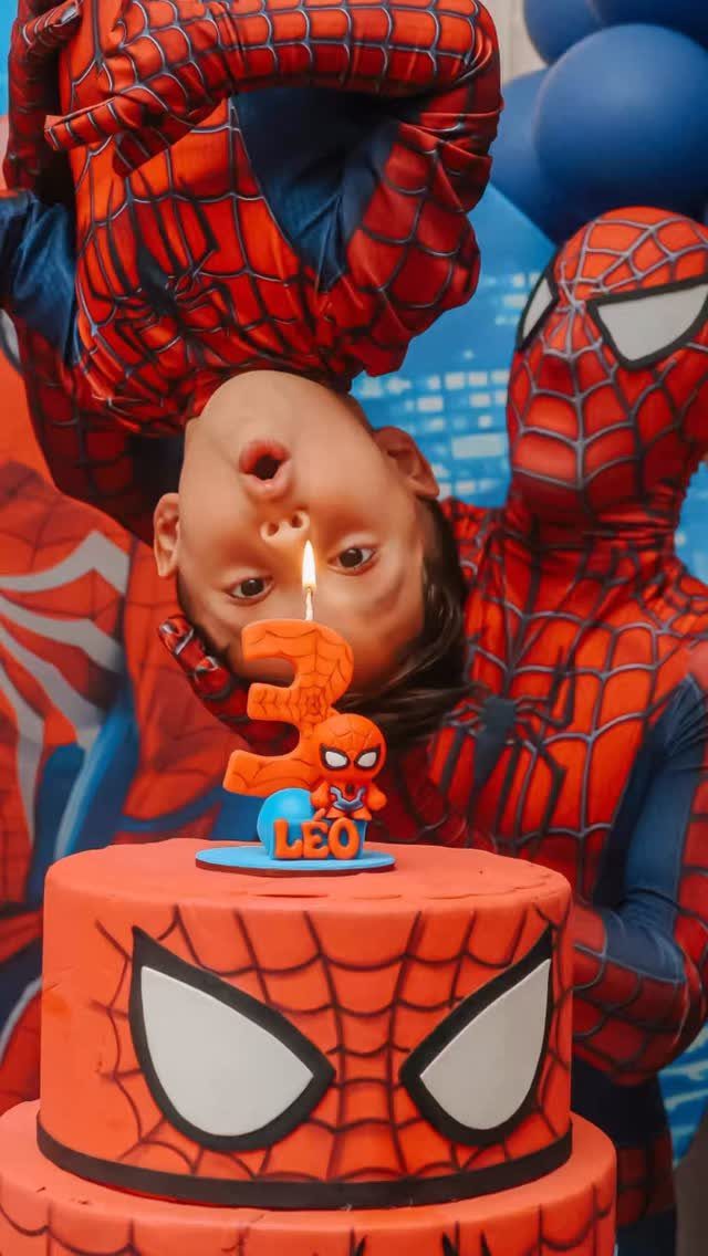 Child and adult in Spider-Man costumes celebrating with a themed birthday cake.