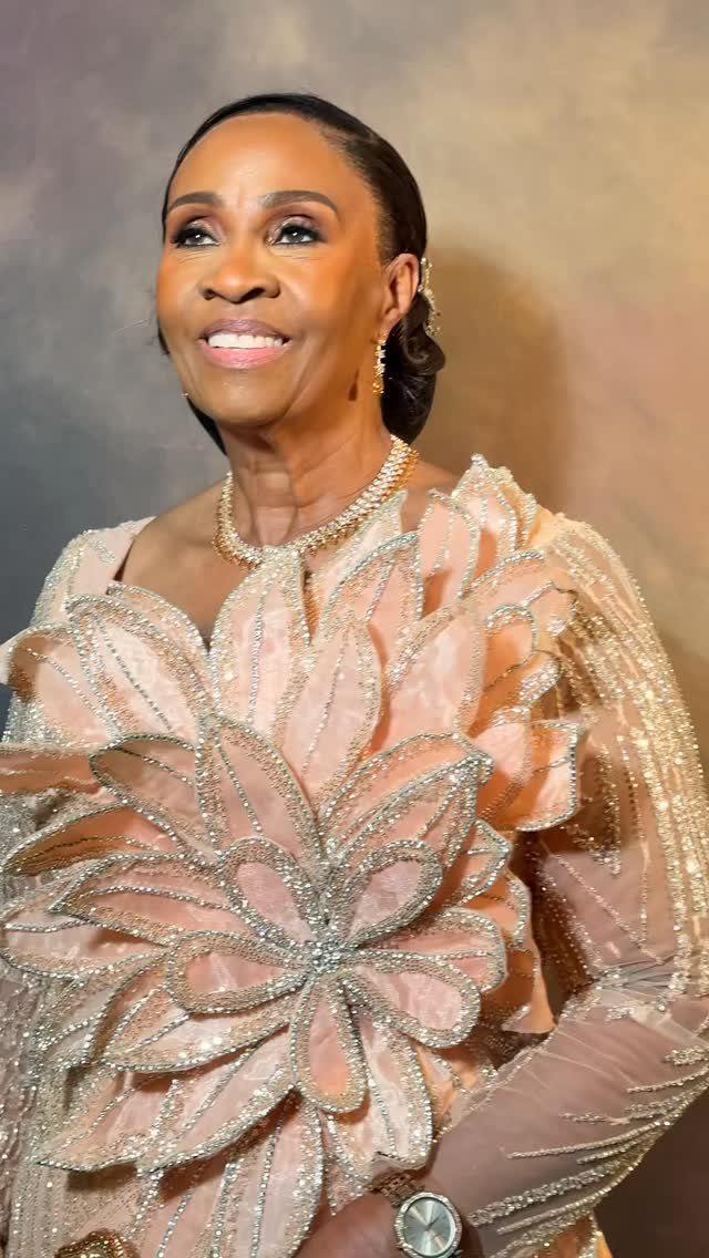 Mature woman wearing an ornate peach dress with large shimmering floral appliqués