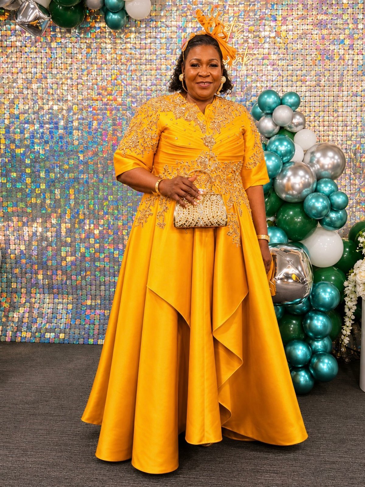 Woman in a gold embroidered gown and fascinator posing before a festive backdrop