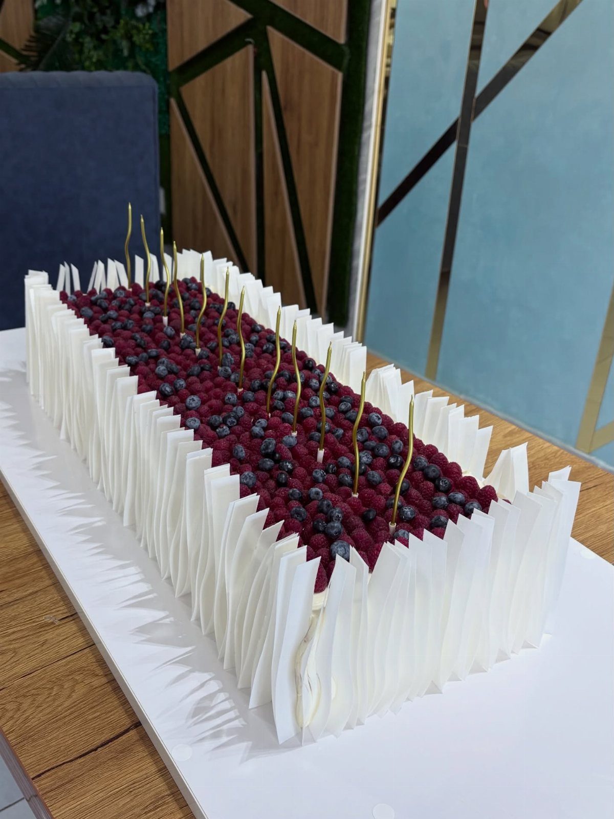 Rectangular sheet cake topped with fresh berries and white chocolate shards.