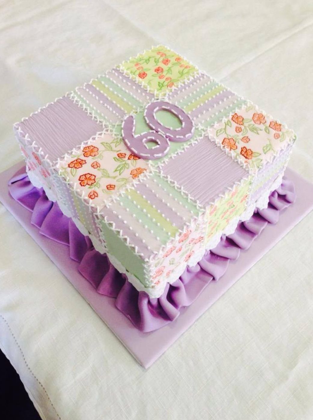Patchwork quilt cake with purple number 60 and purple fondant ruffle base.