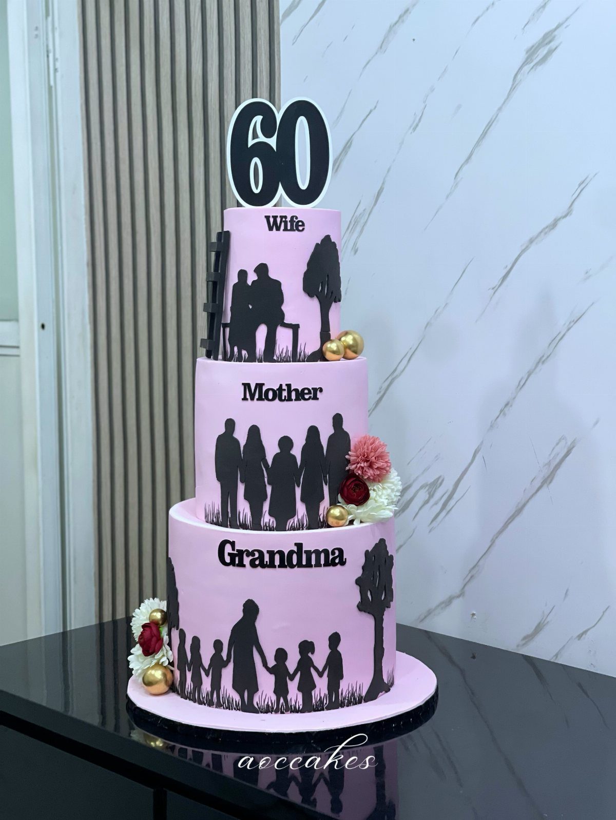 Three-tiered pink 60th birthday cake with black family silhouettes and floral accents.