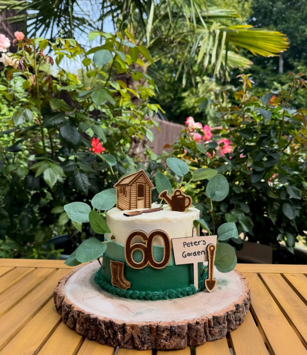 Two-tier gardening themed cake with a small shed and Peter's Garden sign.