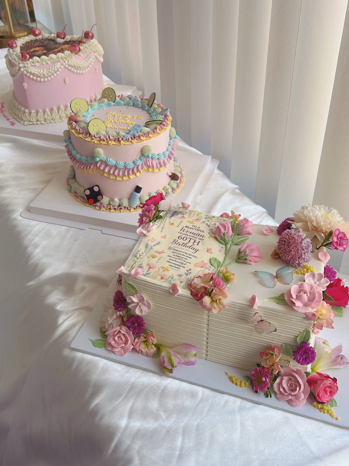 Book shaped cake decorated with pink flowers and butterflies on a white table