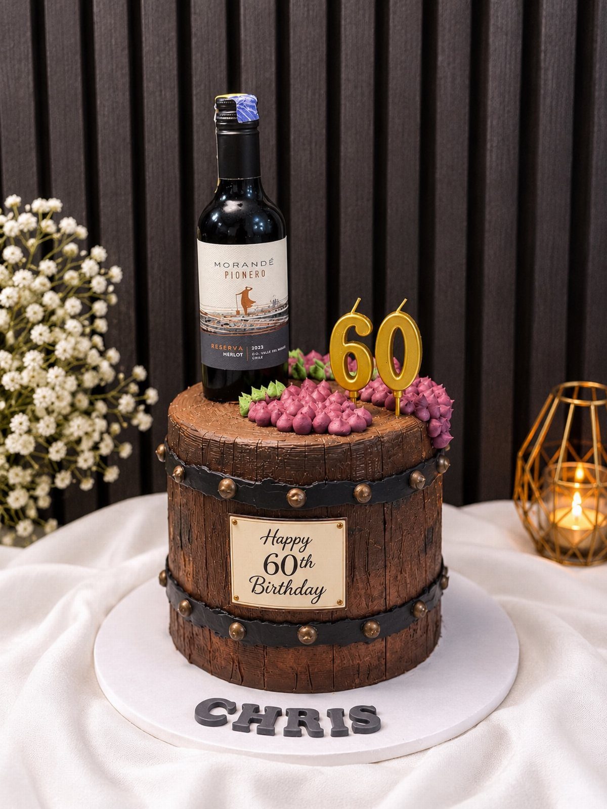 Wine barrel cake with a red wine bottle, purple grapes, and gold 60 candle.