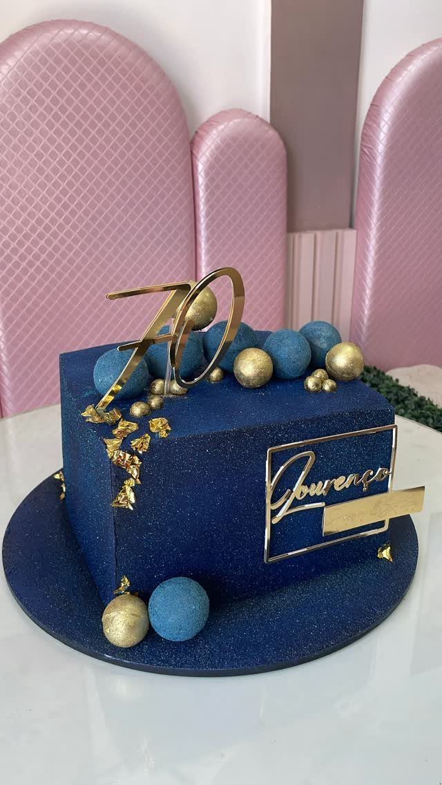 Dark blue glittery 70th birthday cake with gold spheres and name plaque.