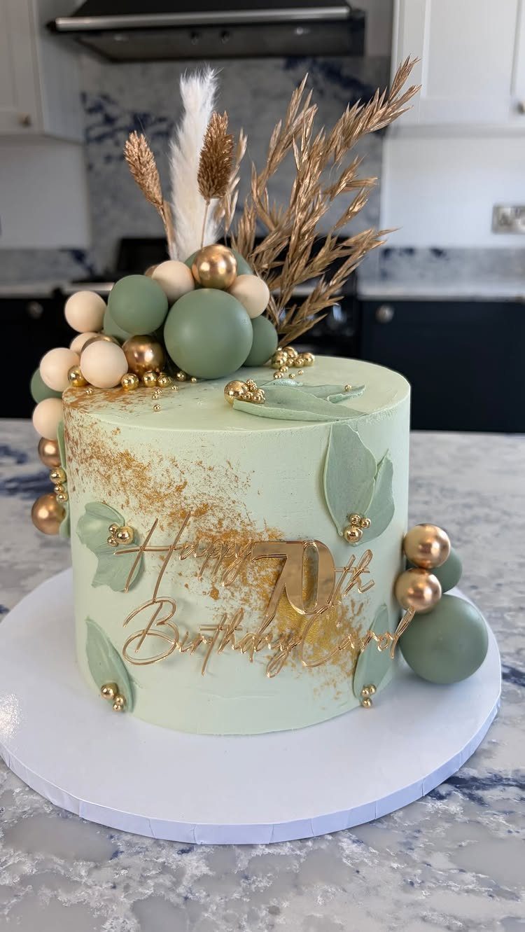 Light green 70th birthday cake decorated with gold leaf and botanical elements