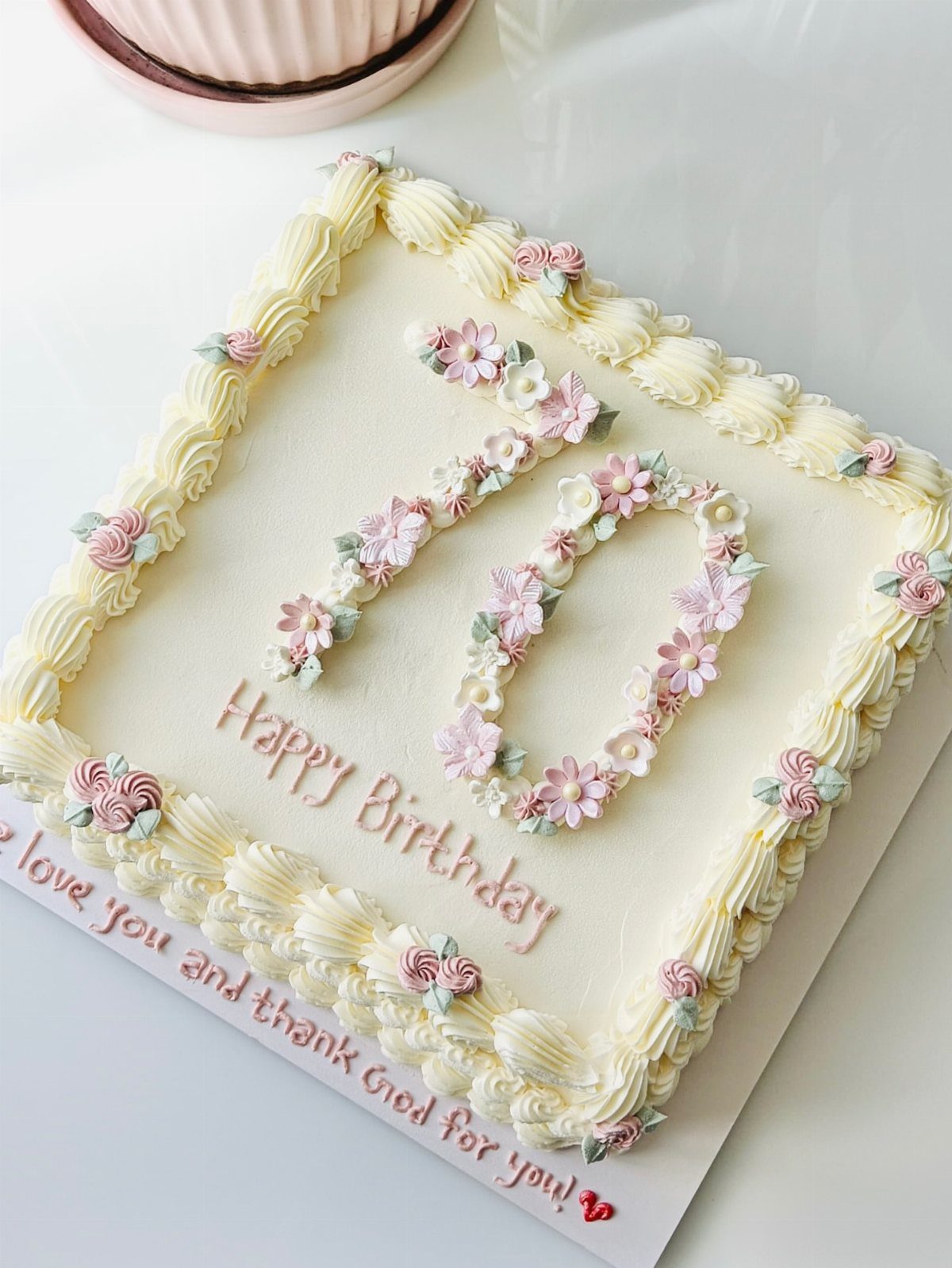 Square white birthday cake with number 70 made of small pink and white flowers