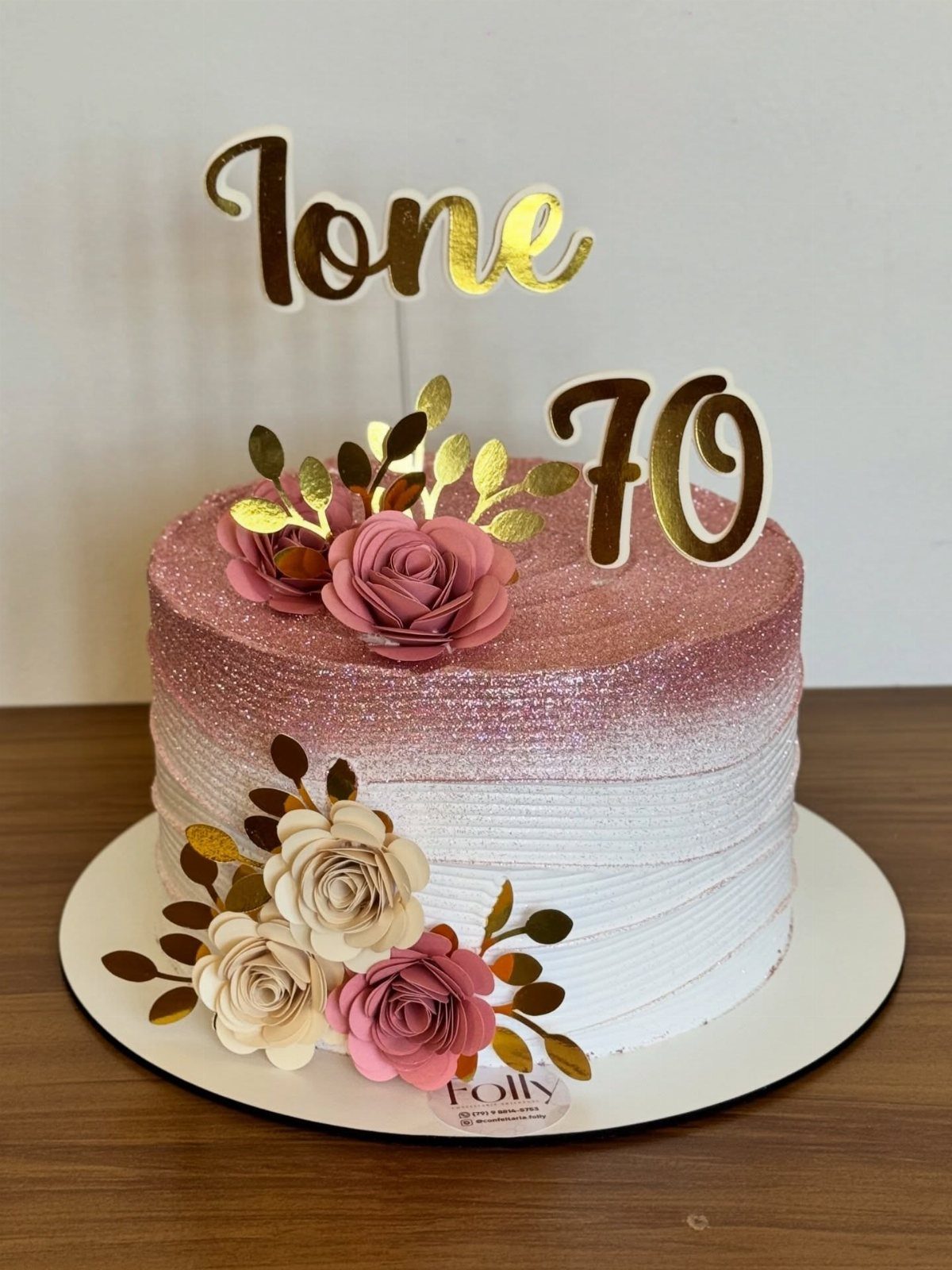 Pink and white ombre cake decorated with roses and gold 70th birthday toppers.