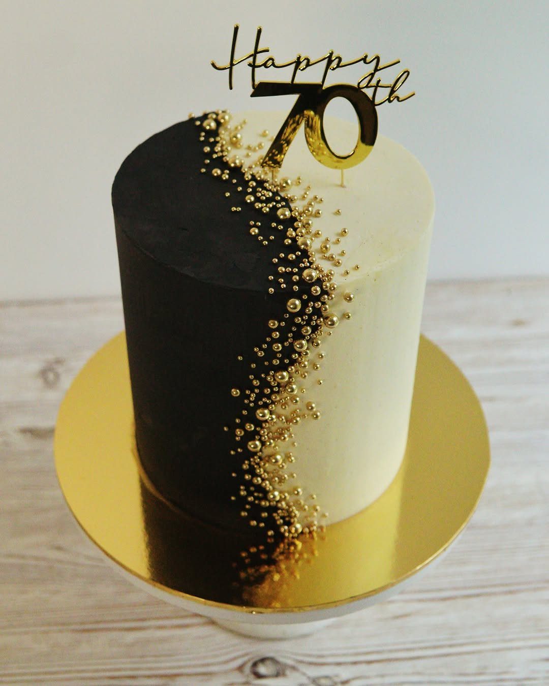 Black and white cake with gold sprinkles and a Happy 70th topper