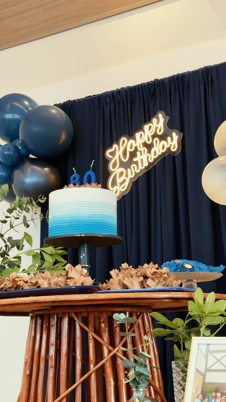 Blue ombre birthday cake with number 80 candles on a decorated dessert table.