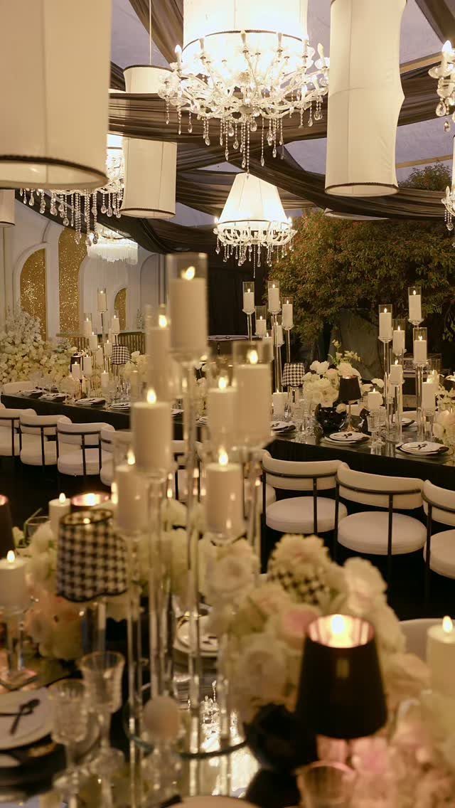 Elegant dining table set with white flowers, pillar candles, and crystal chandeliers.