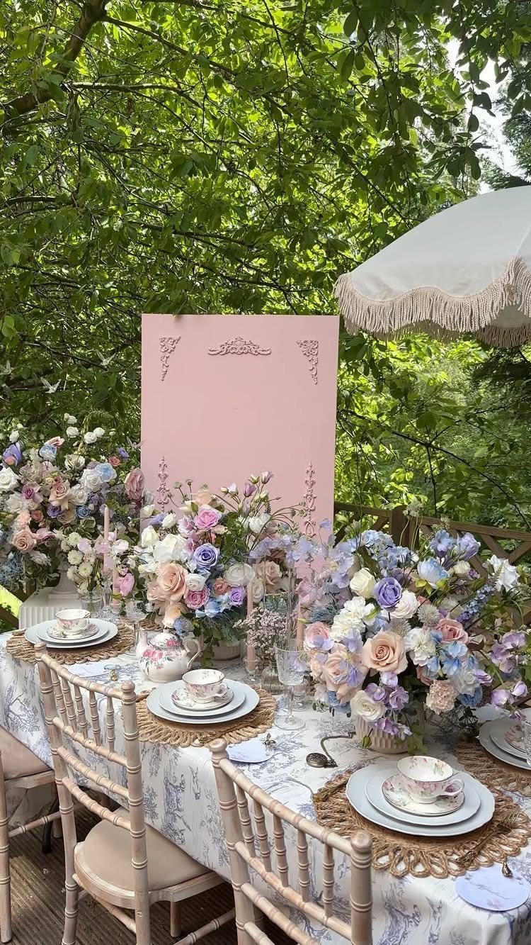 Elegant outdoor table setting with pastel rose bouquets and a pink backdrop.