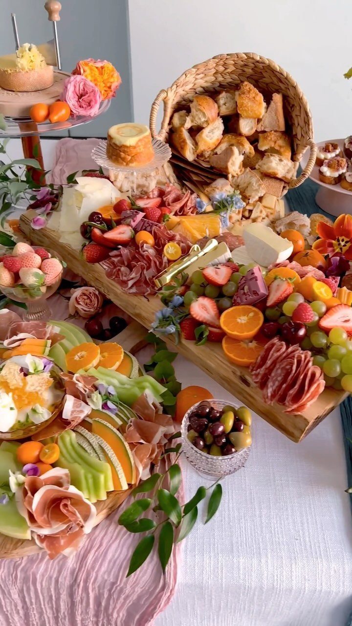 Charcuterie boards with meats, cheeses, and fresh fruits next to a bread basket.