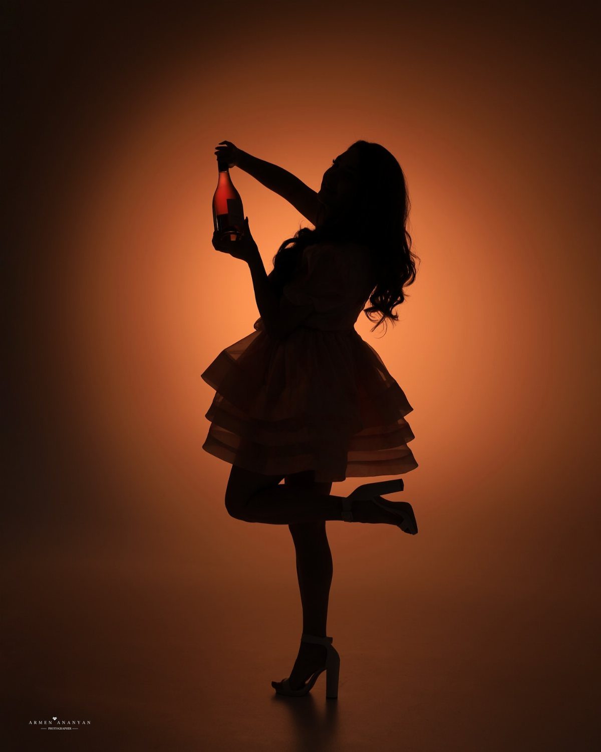 Silhouette of a woman in a tiered dress holding a champagne bottle.