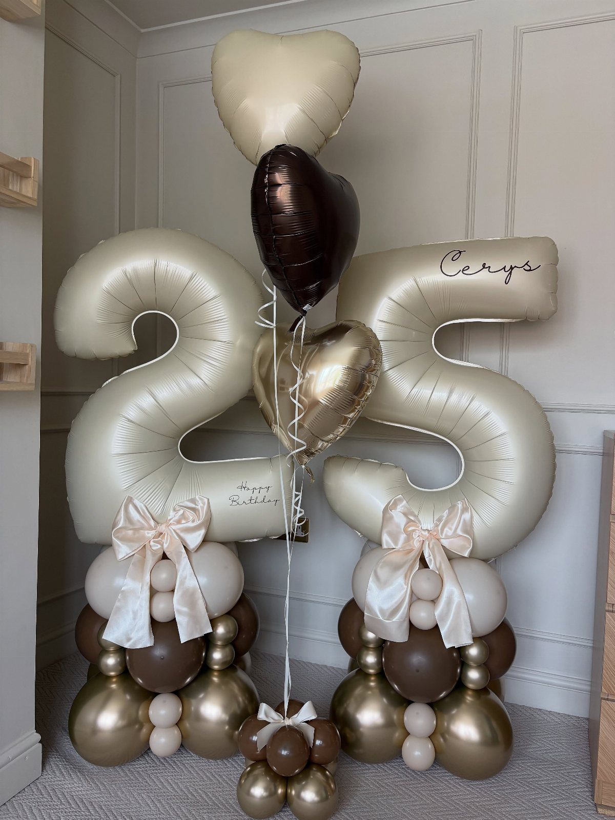 Large cream foil balloons forming the number 25 with heart balloons and bows.