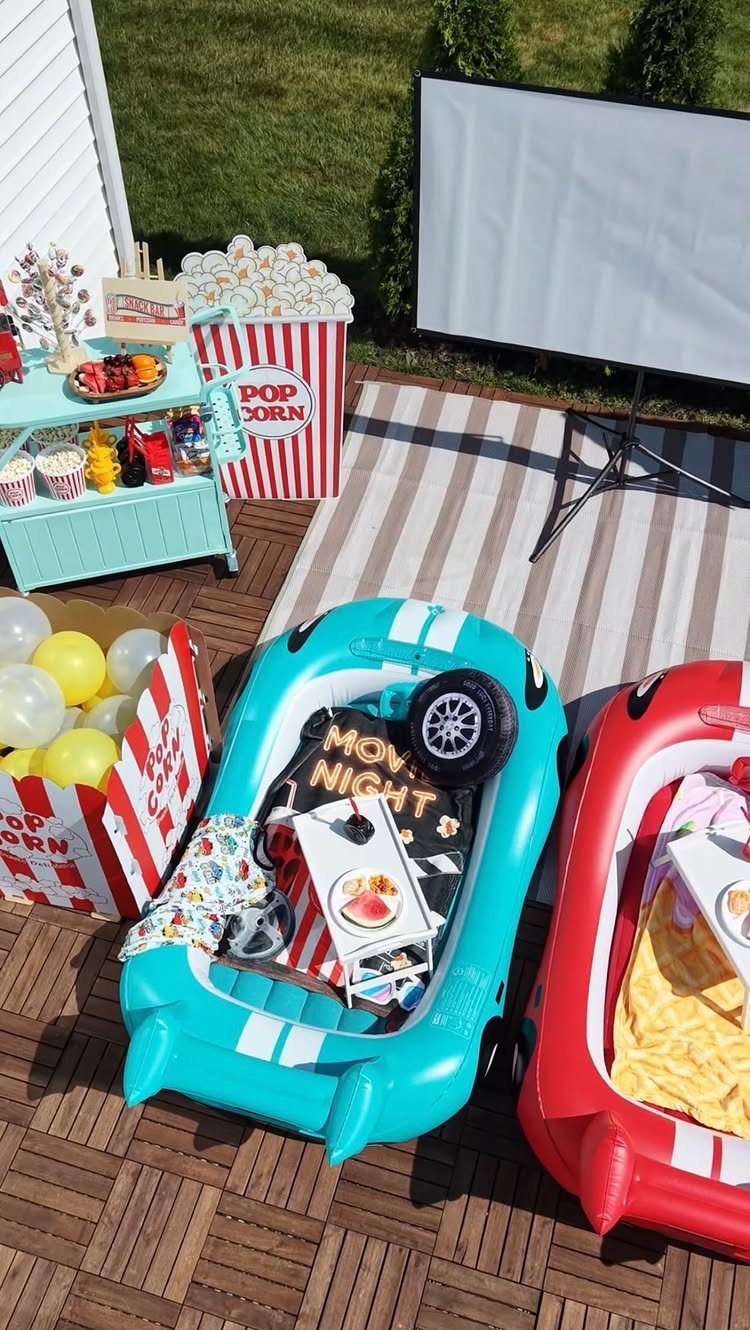Outdoor movie theater setup with projector screen, inflatable seats, and popcorn station.