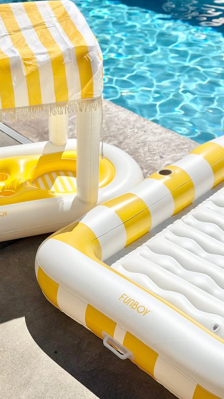 Yellow and white striped inflatable pool floats on a sunny concrete pool deck.