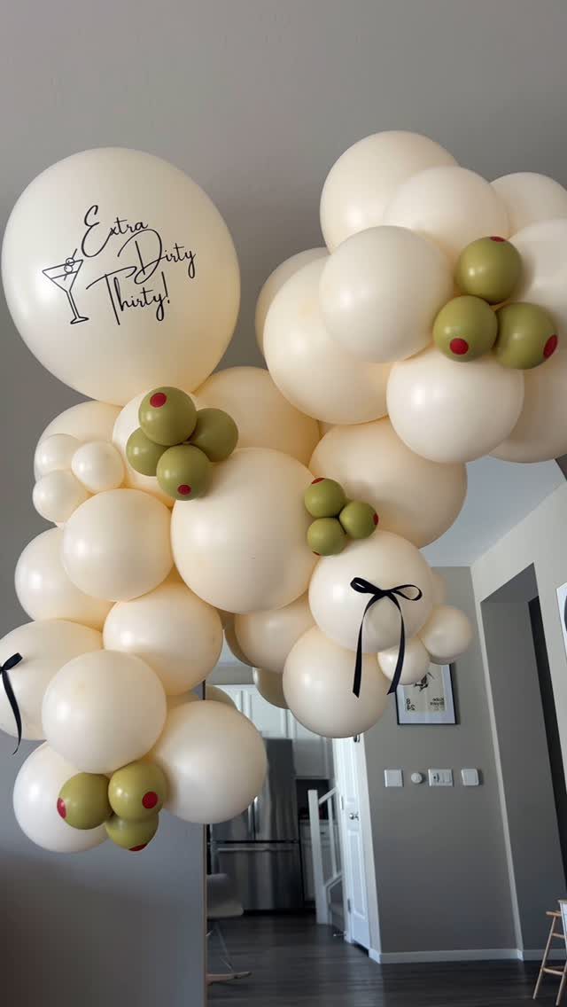 Cream and olive green balloon arch with Extra Dirty Thirty text and martini glass.