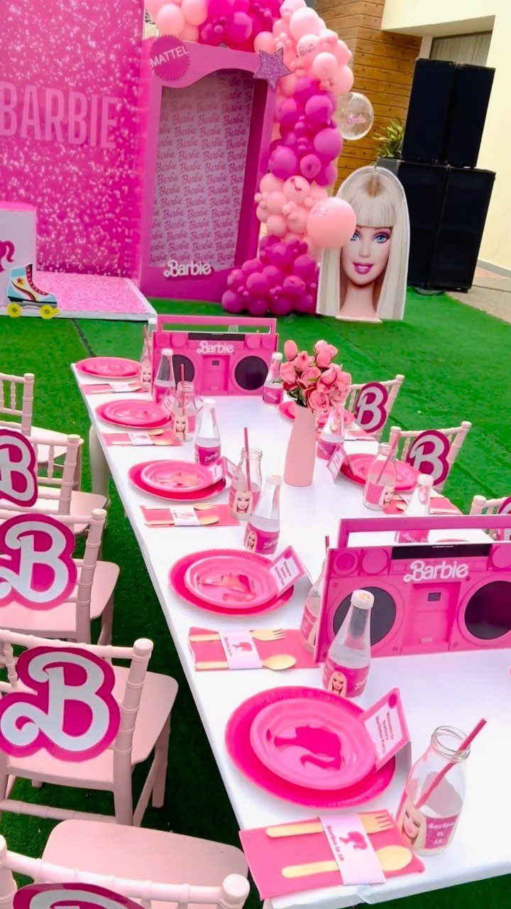 Barbie themed party setup with pink decorations, table settings, and a large doll box.