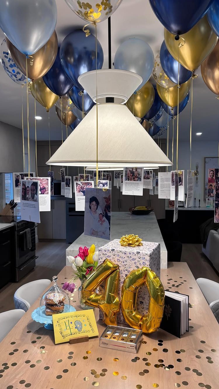 Gold 40 balloons and a gift on a table with hanging memory photos.