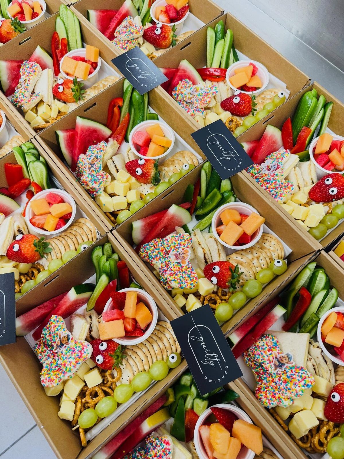 Cardboard snack boxes filled with fruit and cheese decorated with colorful sprinkles