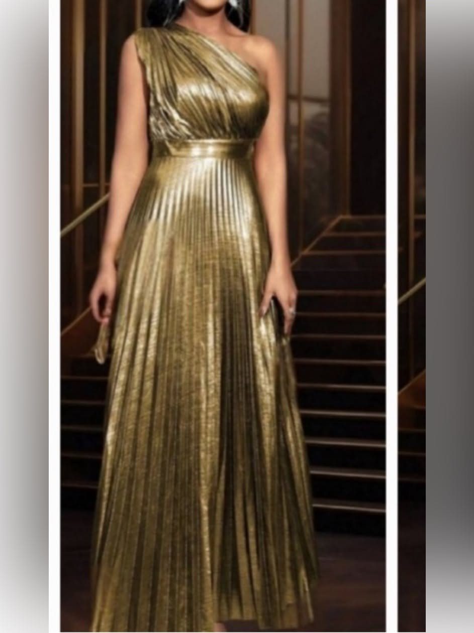 One-shoulder gold metallic pleated maxi dress worn by a person indoors.