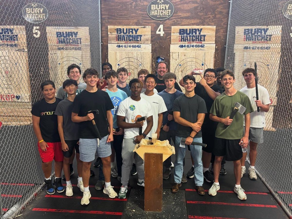 Group of teenage boys posing with axes at an axe-throwing venue.