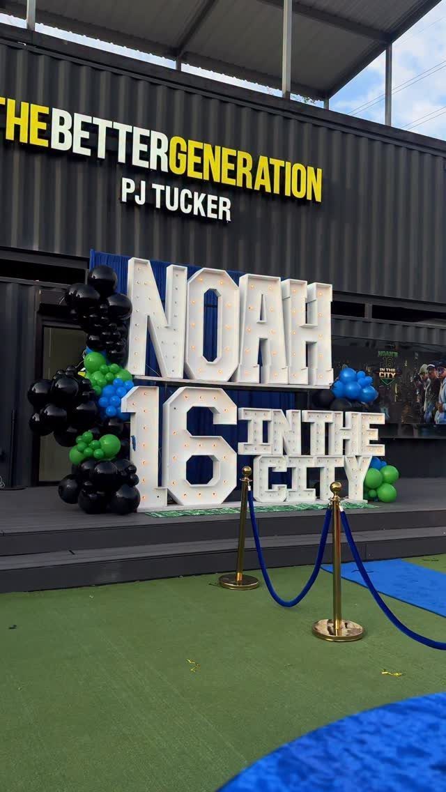 Large white 3D letters spelling Noah 16 in the City with colorful balloons.