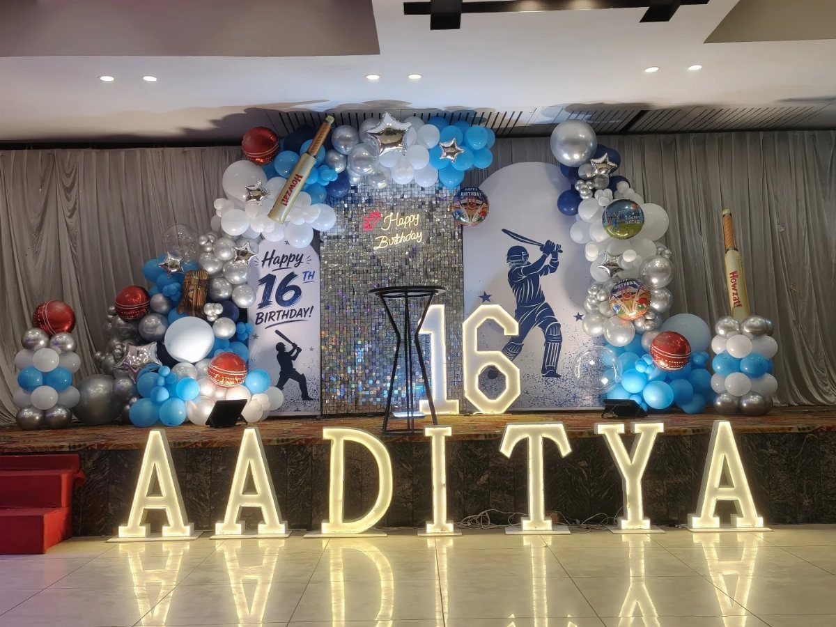 Cricket themed 16th birthday party decoration with balloons, bats, and illuminated name letters.