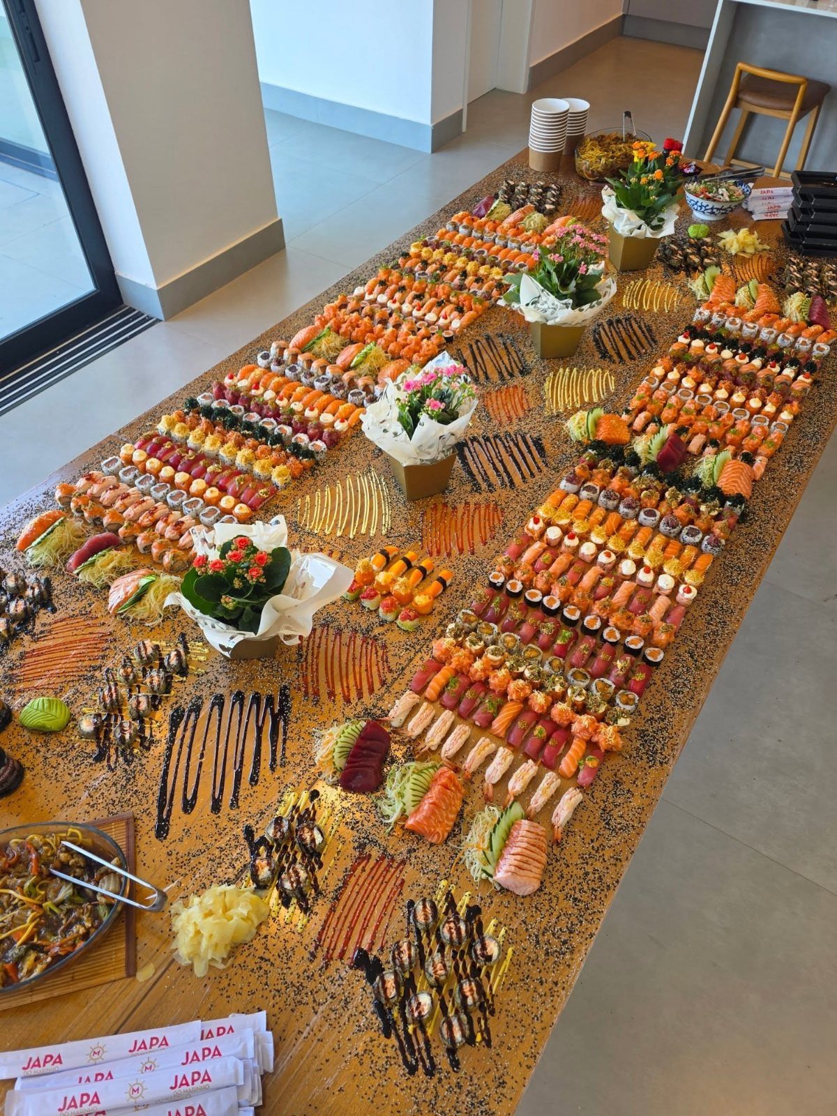 Massive sushi platter spread on a gold glitter tablecloth for a party celebration.