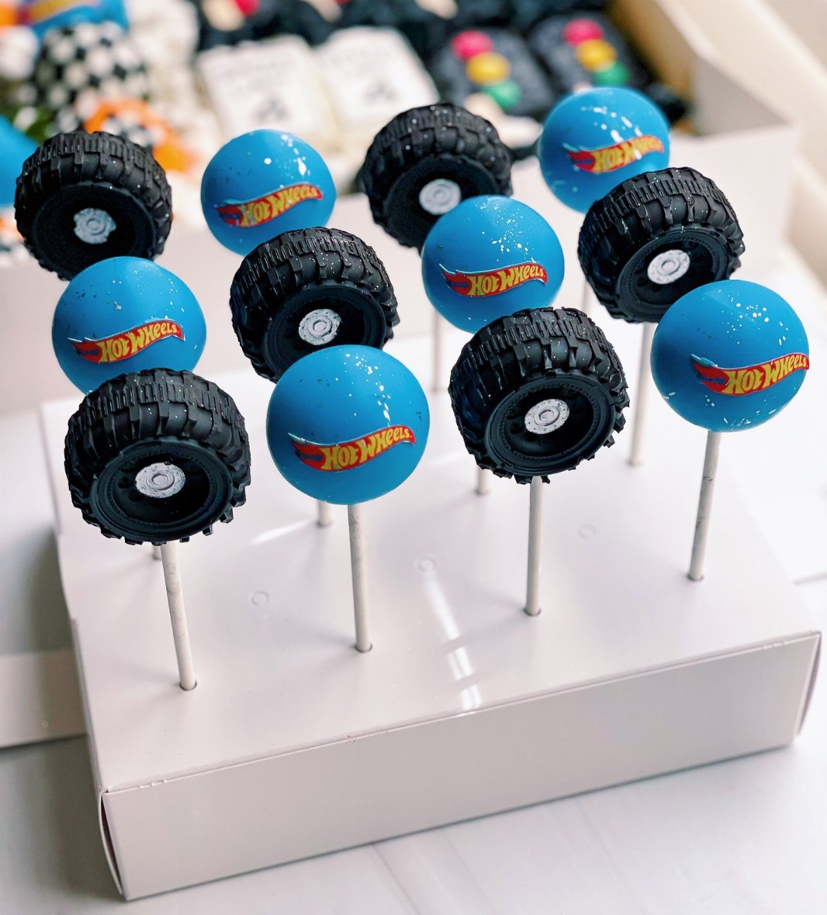 Hot Wheels themed cake pops shaped like tires and blue spheres in a box