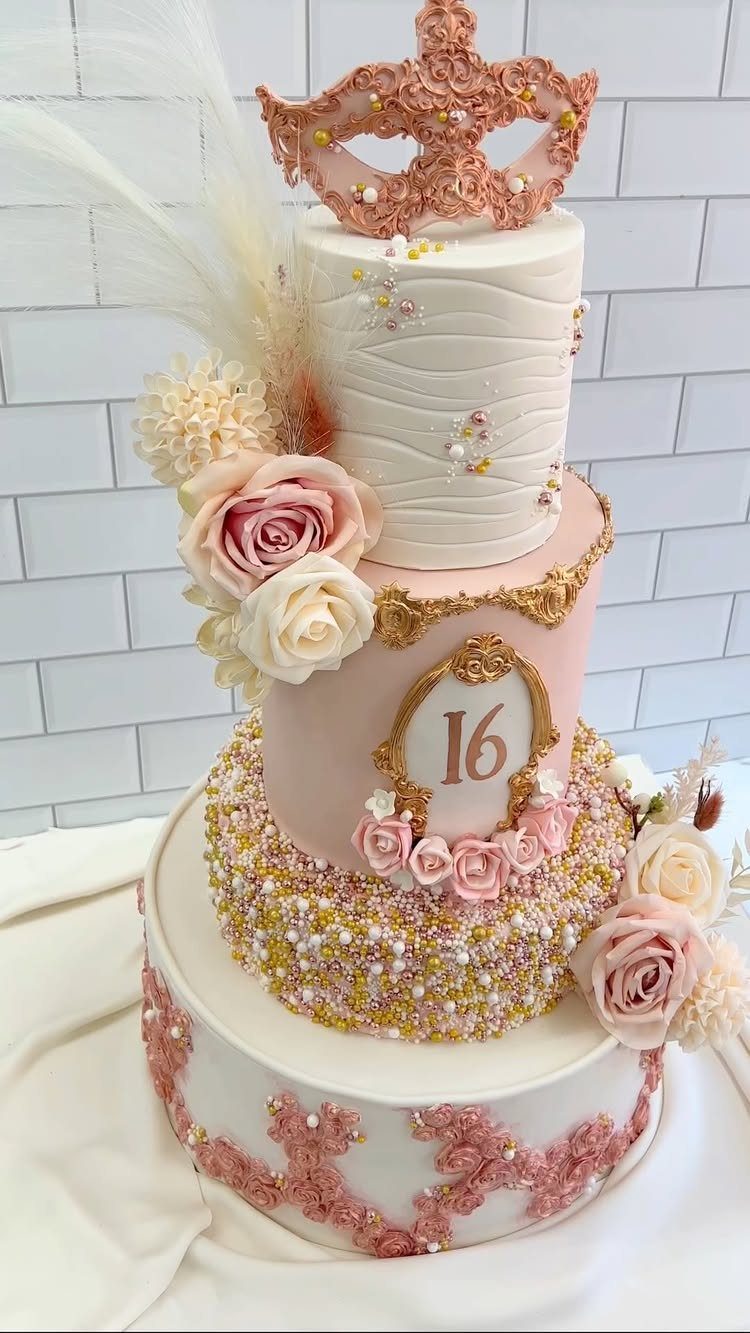 Multi-tiered pink and white cake with a gold masquerade mask and number 16.