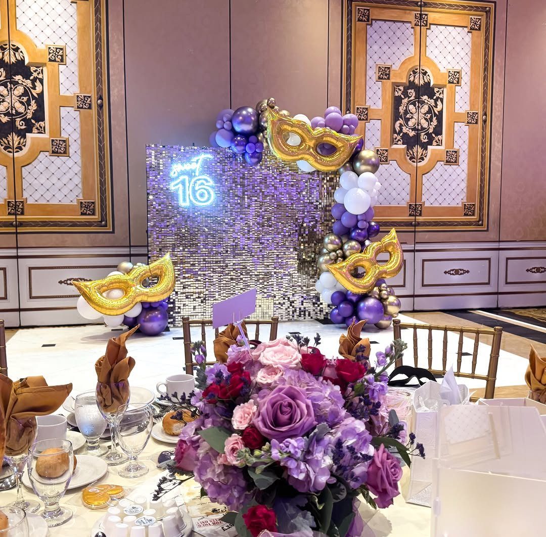Purple sequin backdrop with neon 16 sign and gold masquerade mask decorations.