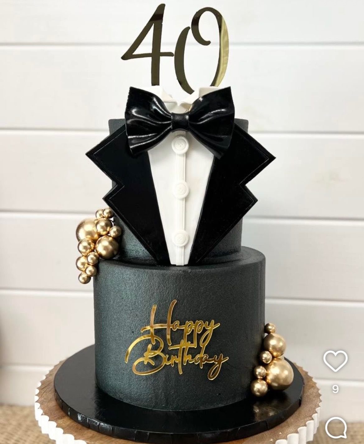 Two-tier black birthday cake designed as a tuxedo with gold 40 topper.