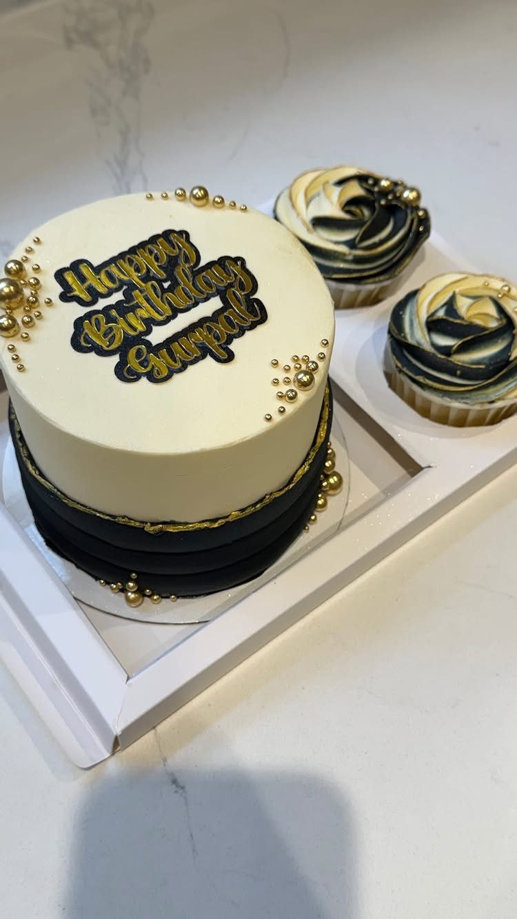 White and black layered birthday cake with gold pearls and matching cupcakes