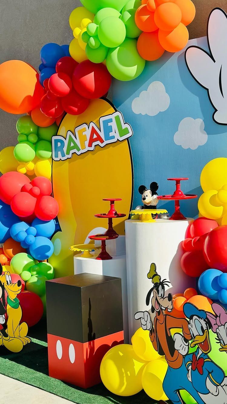 Colorful Mickey Mouse party decor with balloon arch and character cutouts for Rafael.