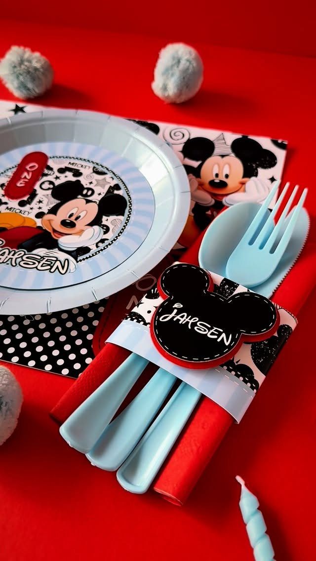 Mickey Mouse themed party plate and blue cutlery set on red background