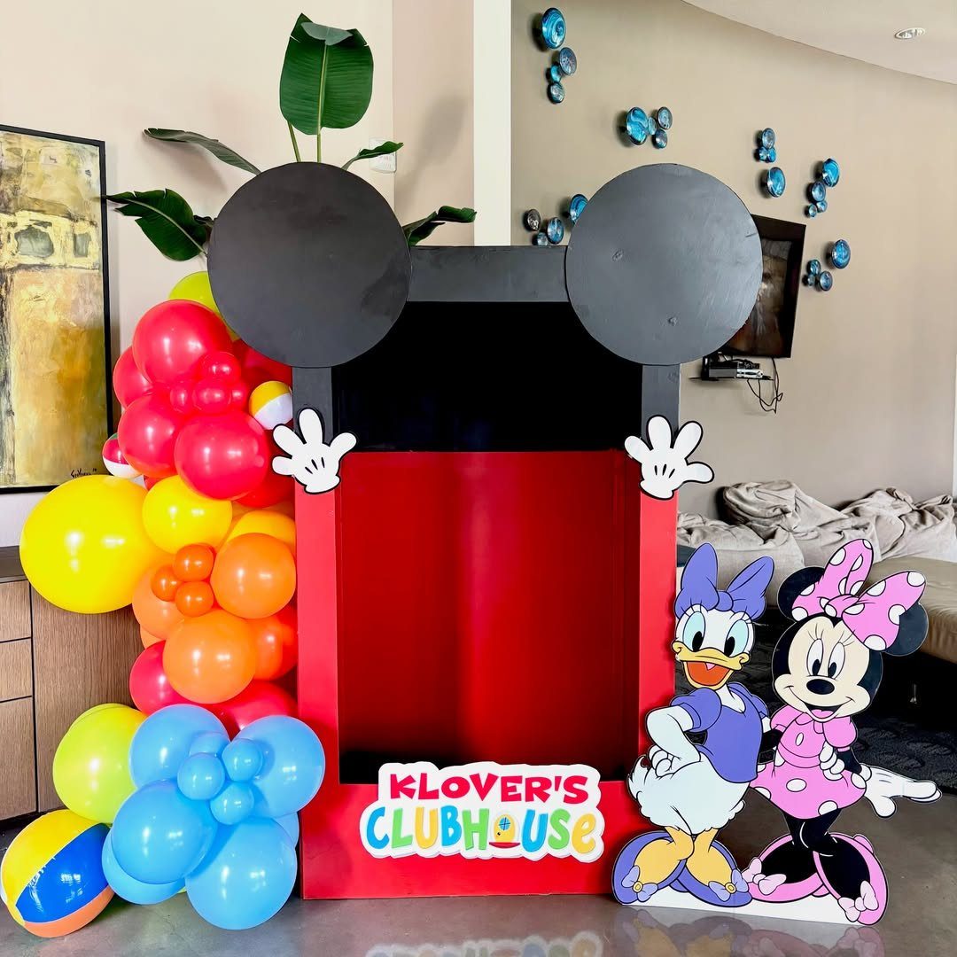 Mickey Mouse themed photo booth frame with colorful balloons and character cutouts.