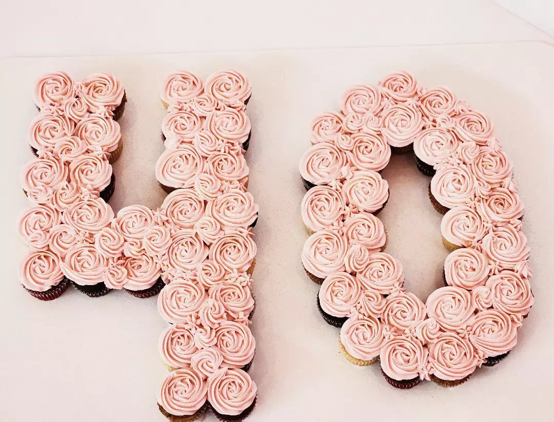 Cupcake cake shaped like the number 40 with pink frosting rose swirls.