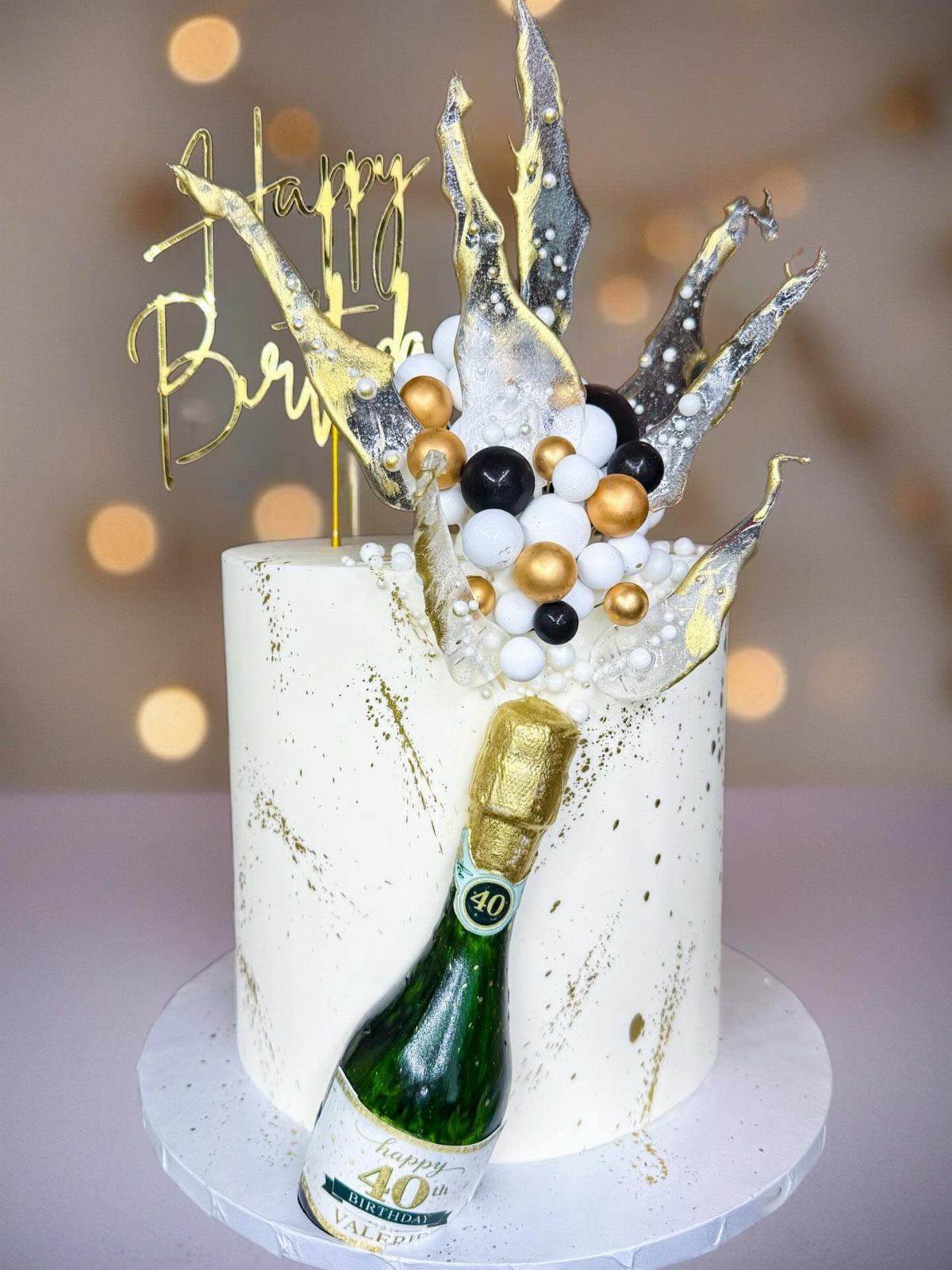 White birthday cake with a champagne bottle and gold and silver decorations.