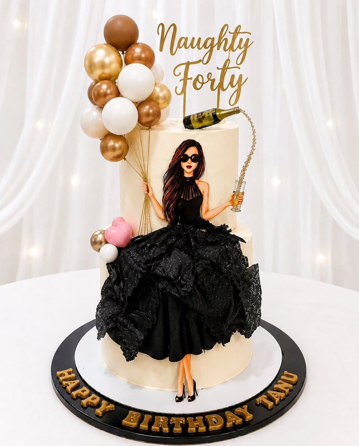 Two-tier white birthday cake with a woman in a black ruffled dress and balloons.