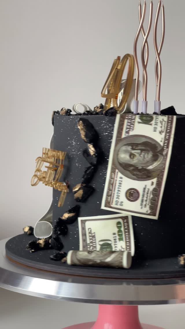 Black 40th birthday cake decorated with gold accents and edible dollar bills.