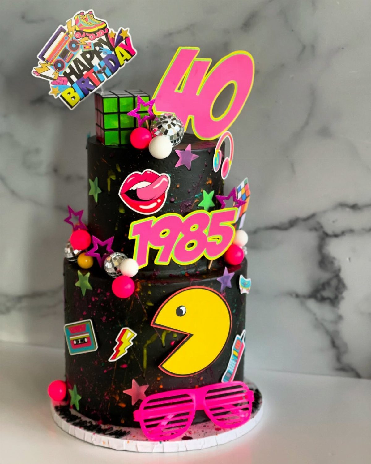 Neon 80s themed two-tier black birthday cake with Pac-Man and number 40 topper.