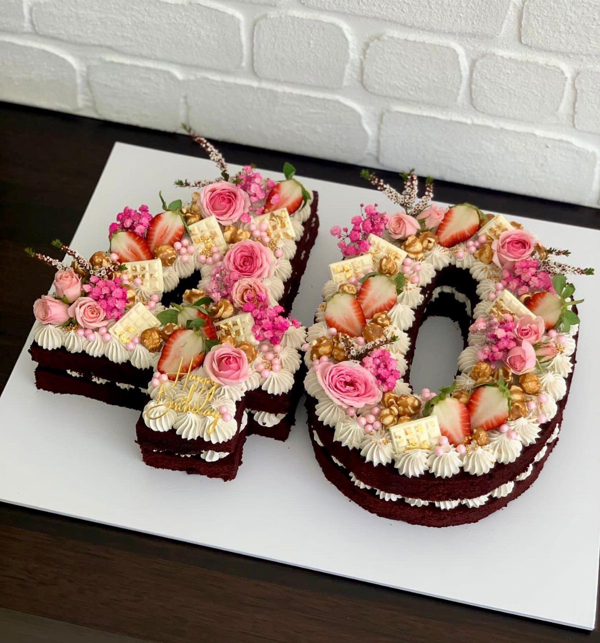 Number 40 red velvet cake decorated with pink roses and fresh strawberries