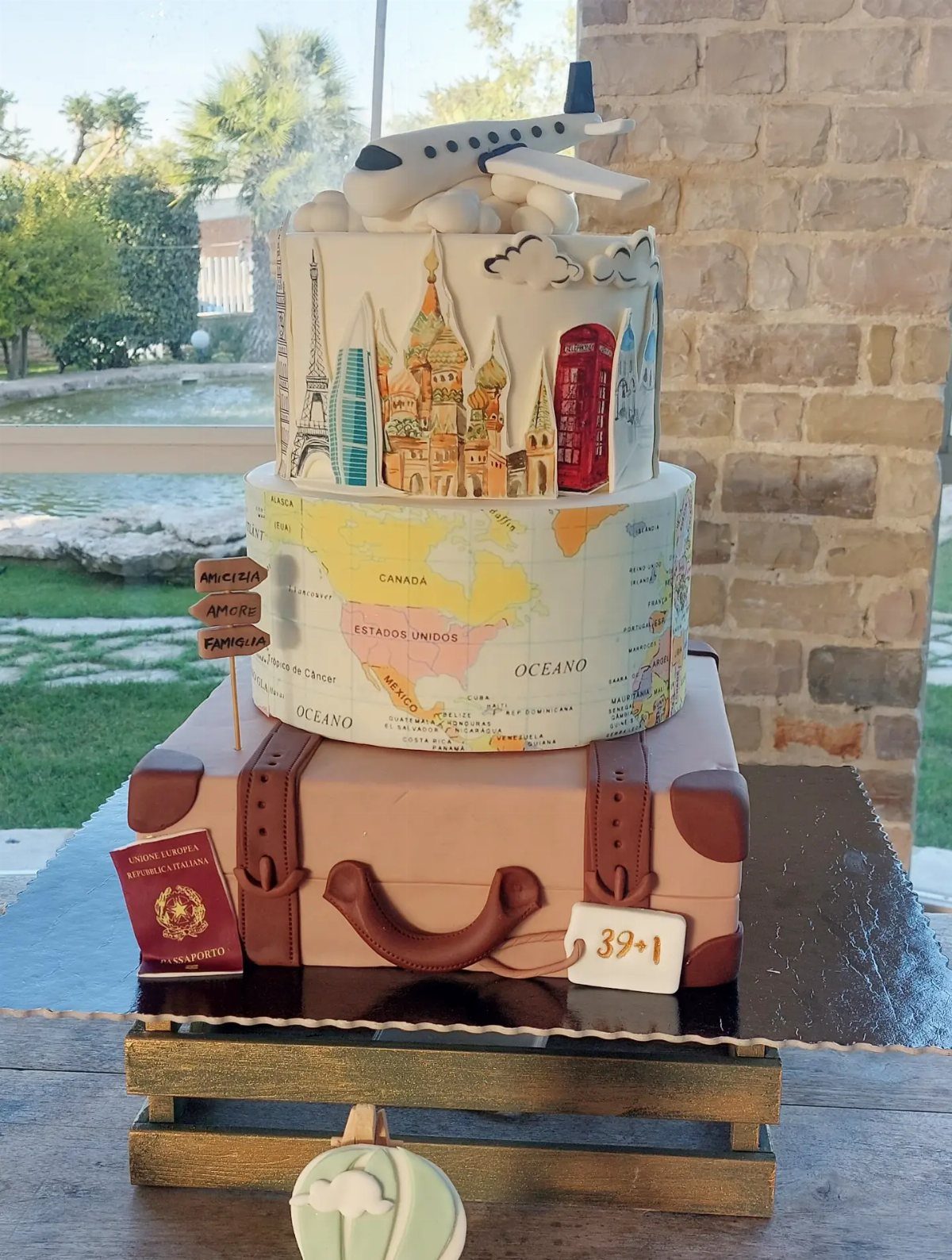 Travel-themed cake shaped like a brown suitcase with a world map and landmarks.