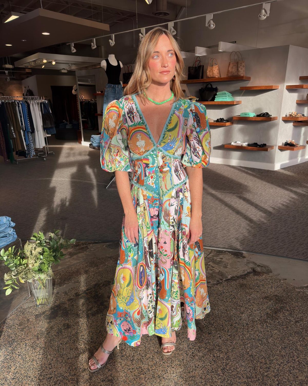 Woman wearing a colorful patterned midi dress with puff sleeves in a boutique.