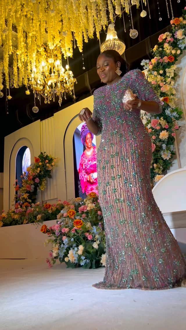Woman in a shimmering purple sequined gown posing in a floral decorated venue.